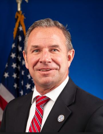 Image of Director Schaefer in front of a United States flag