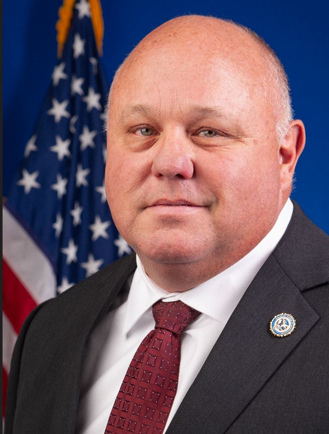 Deputy Director Ray Butler in front of US flag