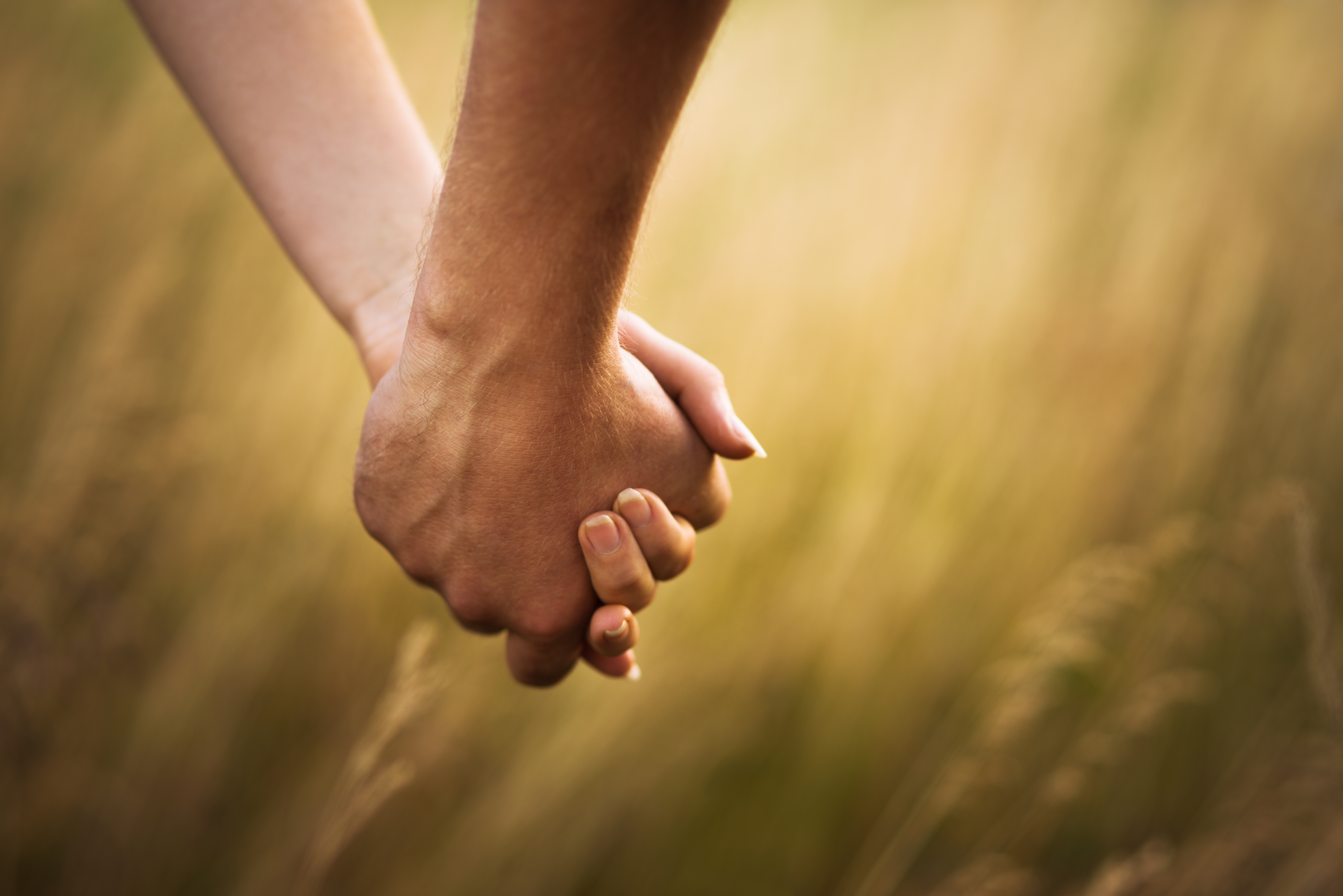 Two hands hold each other against a background of grass